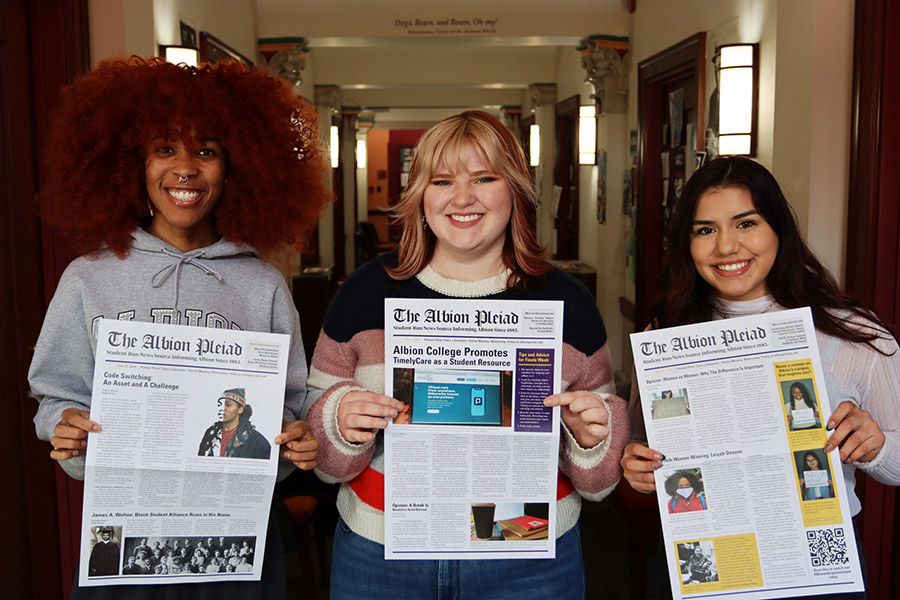 Three students posing with newspapers.