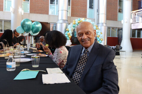 Dr. James Curtis wearing a suit and tie at his 100th birthday celebration in the Albion College Science Complex Atrium.