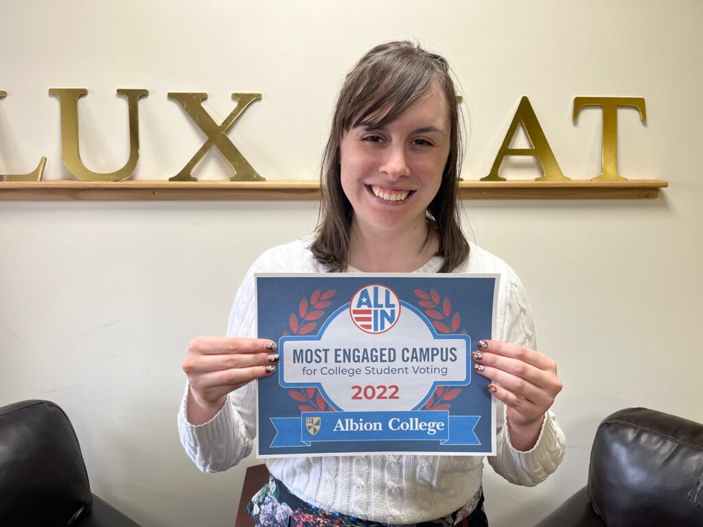 Elizabeth holds an ALL IN certificate that reads Most Engaged Campus for College Student Voting 2022, Albion College